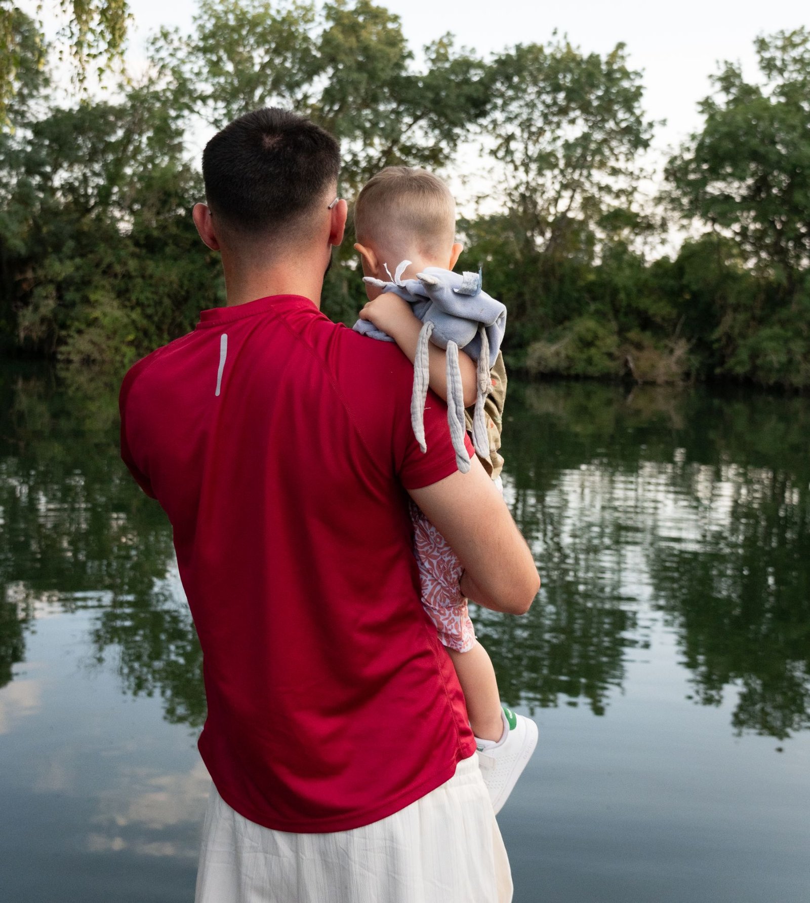 Papa portant son enfant au bord d'un lac