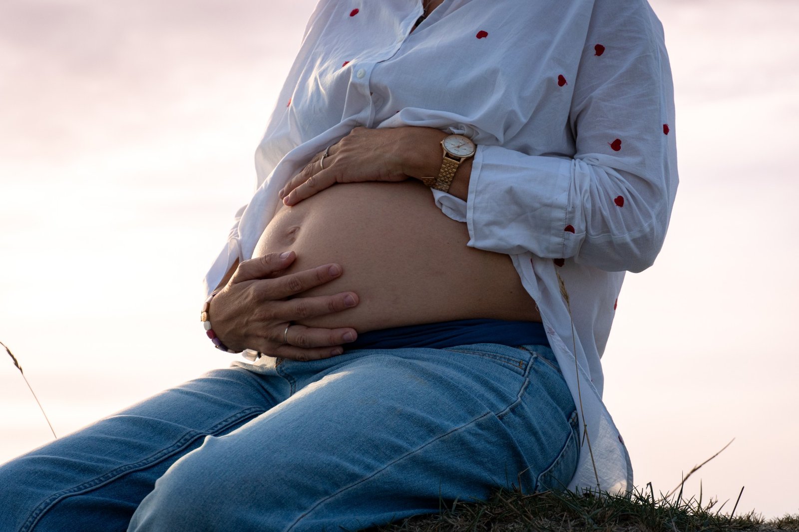 Future maman assise, mains sur le ventre