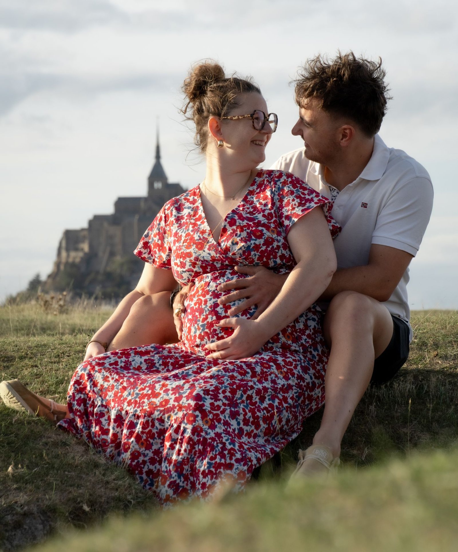 Couple riant assis dans l'herbe devant le Mont